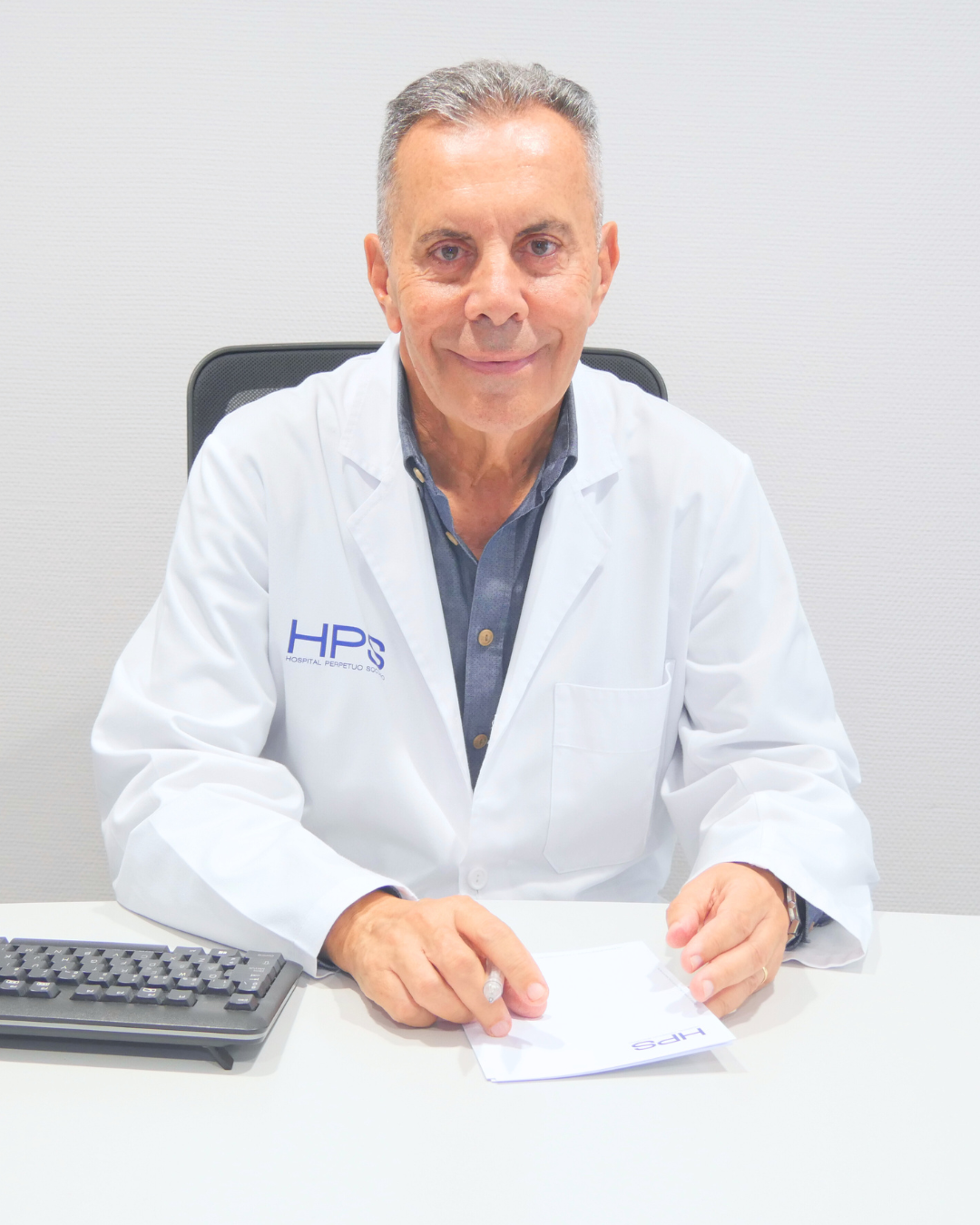 Dr. Julián Castillo, cirujano plástico, sentado en el escritorio de su consulta